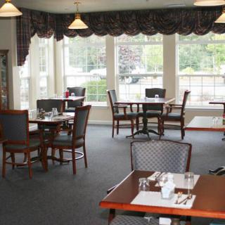 An empty dining room with several tables and chairs, featuring large windows.