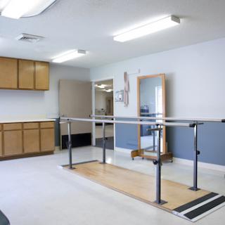A spacious physical therapy room equipped with a barre for rehabilitation exercises.