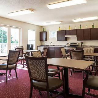 A cozy dining area with several tables and chairs, adjacent to a kitchenette with wooden cabinets and appliances.
