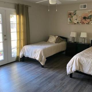 A modern bedroom featuring twin beds, French doors, and stylish decor.