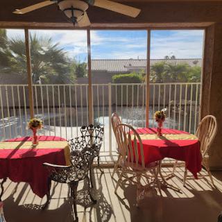 A cozy dining area with red tablecloths, offering a bright view through large windows.