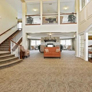 Spacious lobby with carpeted flooring and seating area, featuring a staircase leading to the second floor.