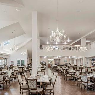 An elegant dining area with chandeliers and neatly arranged tables and chairs.