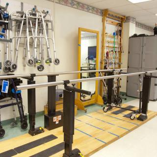 A physical therapy room equipped with parallel bars and various rehabilitation tools.