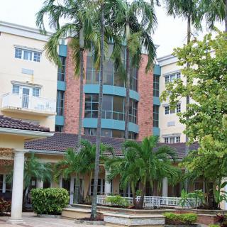A multi-story building surrounded by palm trees and lush greenery.