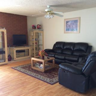 A cozy living room with a leather sofa, recliner, and entertainment setup.
