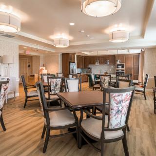 A modern dining area with multiple tables and chairs, featuring stylish lighting and an open kitchen space.