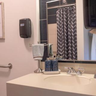 A clean and modern bathroom with a sink, mirror, and shower curtain.