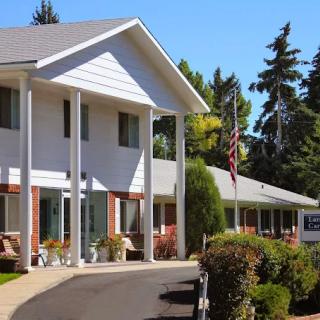 A view of a motel exterior with a well-kept pathway and surrounding trees under a clear blue sky.