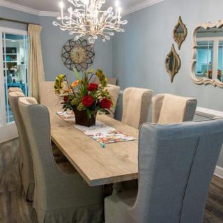 An elegantly decorated dining room with a chandelier and a floral centerpiece on the table.
