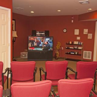 A cozy home theater setup with red chairs facing a large television.