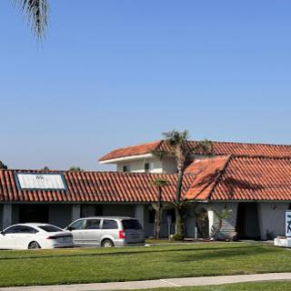 A residential house featuring a red tile roof and palm trees under a clear blue sky.