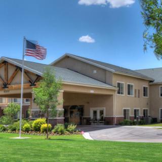 A well-maintained building with an American flag and a green lawn under a blue sky with clouds.