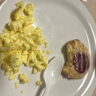 A plate with scrambled eggs and a pastry.