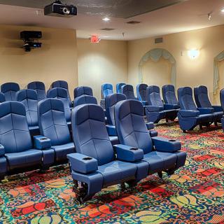 Empty movie theater with comfortable seating and colorful carpet.