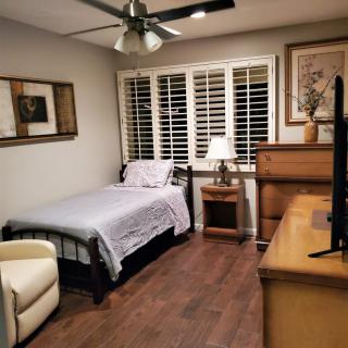 A cozy bedroom with a single bed, nightstand, and wooden furniture.