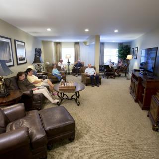 A cozy living room with several people relaxing and watching television.