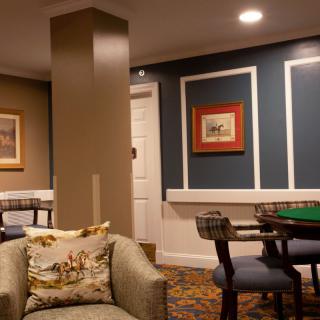 A cozy living room featuring a poker table, chairs, framed artwork on the walls, and comfortable seating.