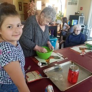 A joyful cooking session where a young girl helps elderly women in the kitchen.