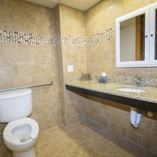 A modern bathroom with tile walls, a toilet, a sink, and a mirror.