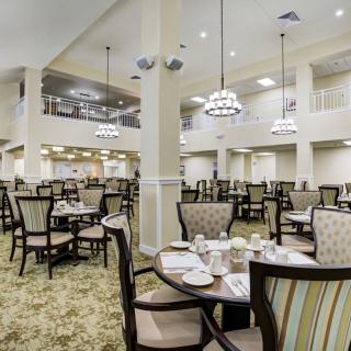 An elegant and spacious dining hall with neatly arranged tables and chairs under stylish chandeliers.