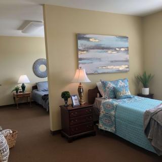 A cozy bedroom with twin beds, decorated with a large painting and soft lighting.