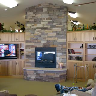 A cozy living room with a stone fireplace and built-in shelves surrounding a television.