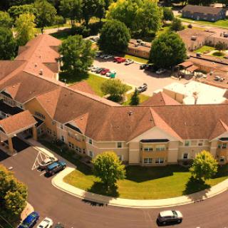Aerial view of a residential complex surrounded by lush greenery and a parking lot.