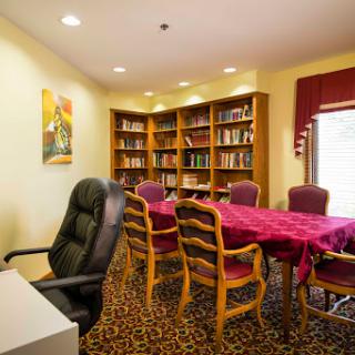 A cozy meeting room featuring a table surrounded by chairs and a bookshelf filled with books.