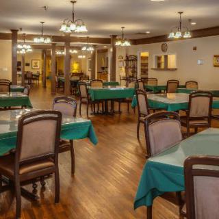 A spacious dining room with neatly arranged tables and chairs, illuminated by elegant chandeliers.