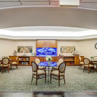 A spacious lobby area with elegant chairs and tables, featuring decorative elements and a large display screen.