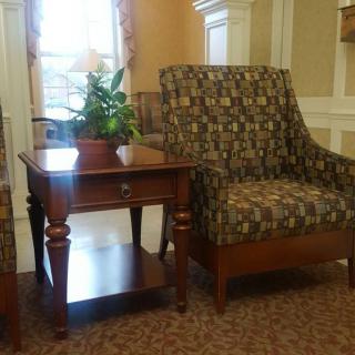 A cozy seating arrangement with a patterned armchair and a wooden side table topped with a plant.