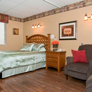 Cozy bedroom with a bed, nightstand, and armchair.