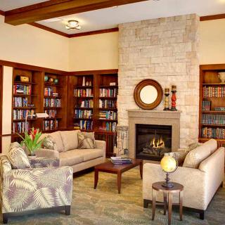 A cozy living room library with comfortable sofas and a warm fireplace, surrounded by bookshelves.