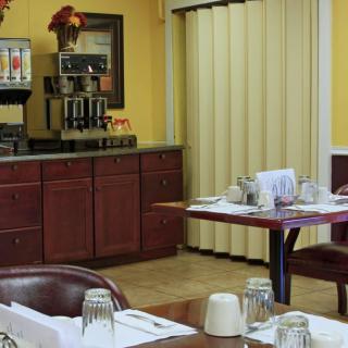 A cozy dining area with tables set for customers, featuring a coffee station in the background.