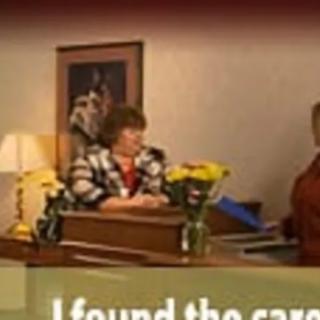 Office scene with people at a desk and flowers on the table.