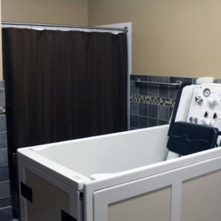 An accessible bathtub with a shower head and curtain in a tiled bathroom.