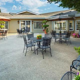 A sunny patio with tables, chairs, and umbrellas outside a residential building.