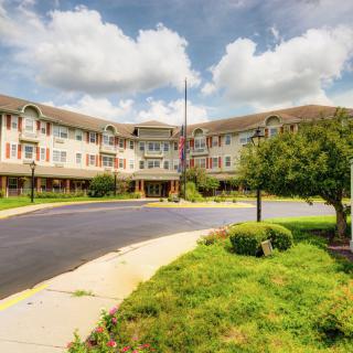 A residential building with a landscaped exterior and a circular driveway under a cloudy sky.