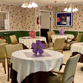 A cozy dining area set up with neatly arranged tables and decorative flowers, perfect for communal meals.