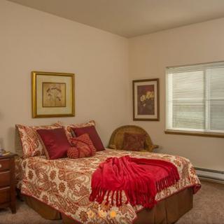 A cozy bedroom with patterned bedding, artwork on the walls, and a window letting in natural light.