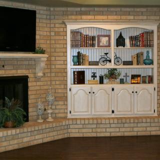 A cozy living room corner with a brick fireplace and built-in bookshelf.