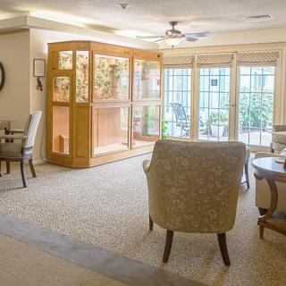 A cozy living room with comfortable chairs, tables, and large windows.