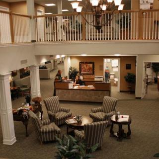A spacious lobby with elegant furniture, a reception desk, and decorative chandeliers.