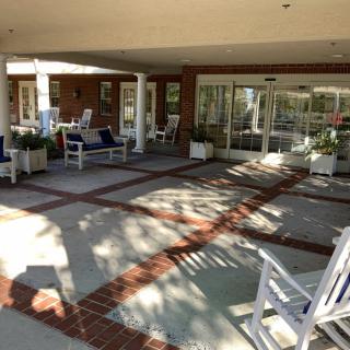 An inviting patio area with rocking chairs and outdoor seating, basking in sunlight.