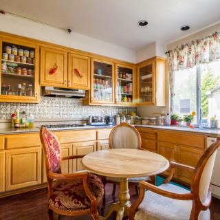 A cozy kitchen with wooden cabinets, a round dining table, and chairs by a sunlit window.