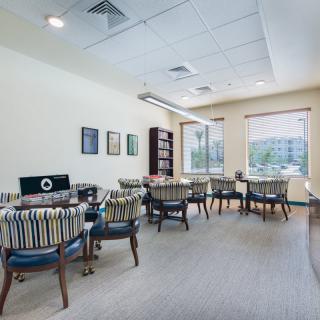A well-lit meeting room with tables and chairs arranged in an office setting.