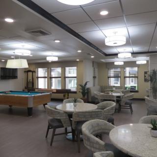 A modern recreation room featuring a pool table and multiple seating areas.