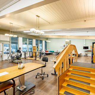 A spacious rehabilitation room equipped with exercise machines, therapy equipment, and stairs for physical therapy sessions.