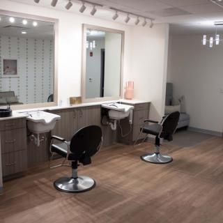 A modern hair salon interior featuring styling chairs, mirrors, and sinks with bright lighting.